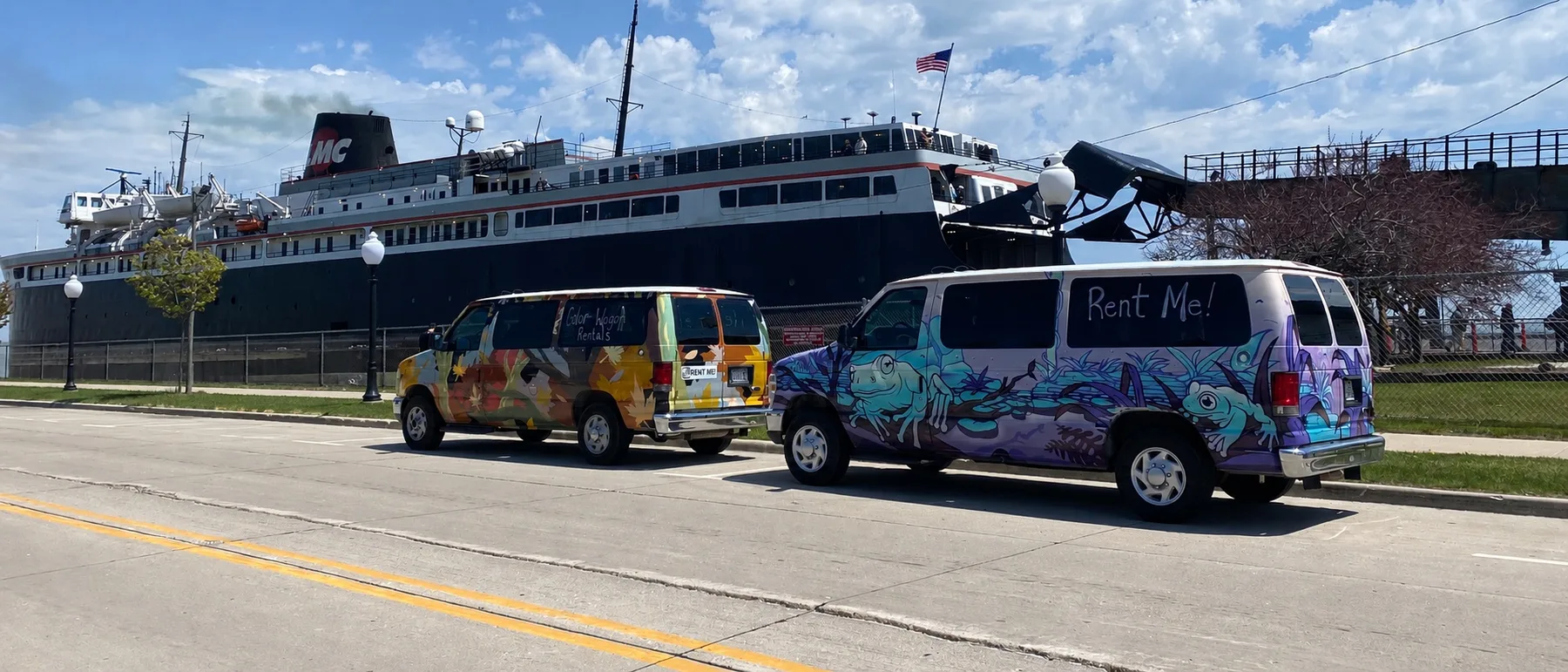 Both hand-painted Color Wagon camper vans parked in front of the SS Badger ferry in Manitowoc